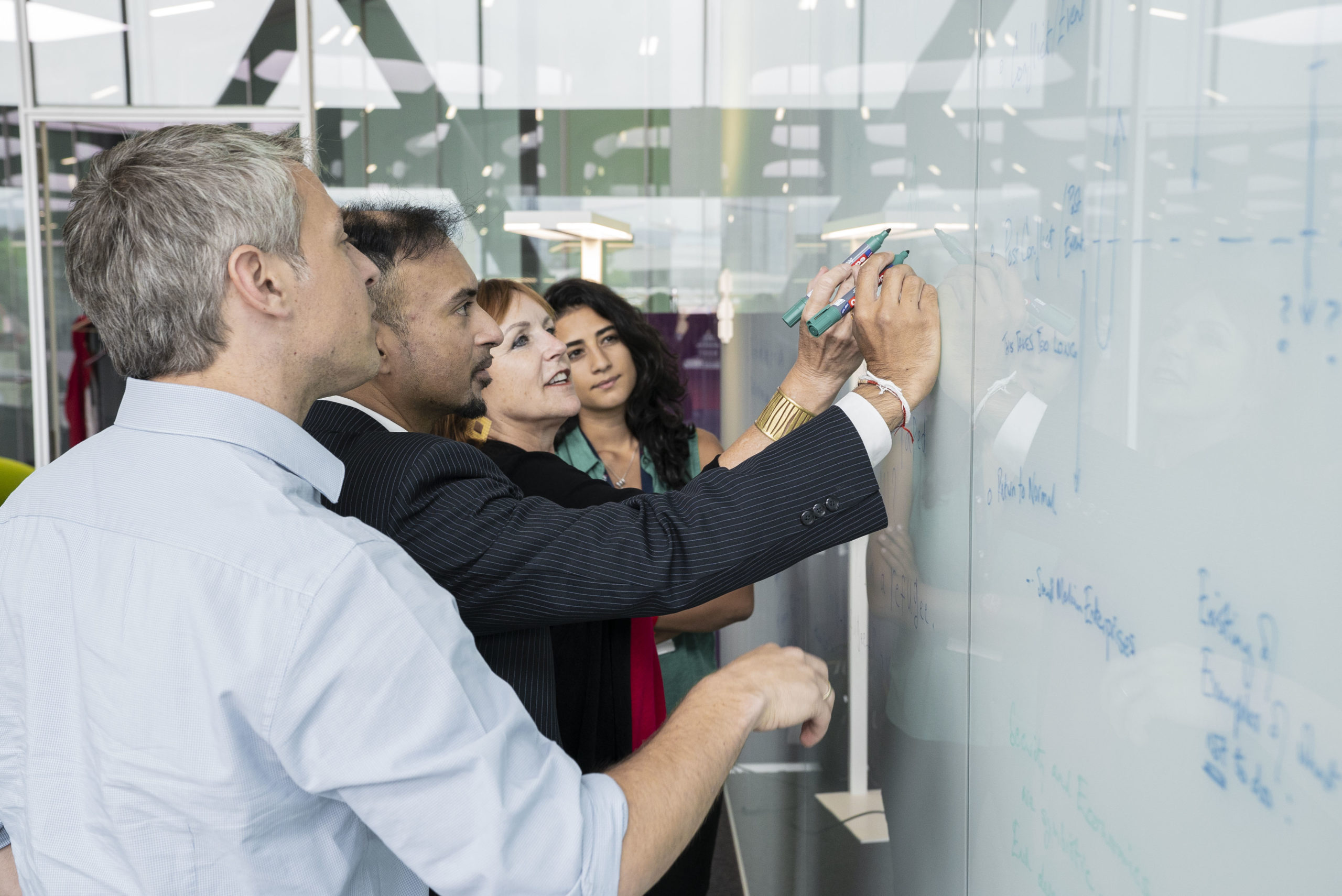 The Geneva Centre for Security Policy team engaging in a collaborative writing session on a whiteboard in their office.