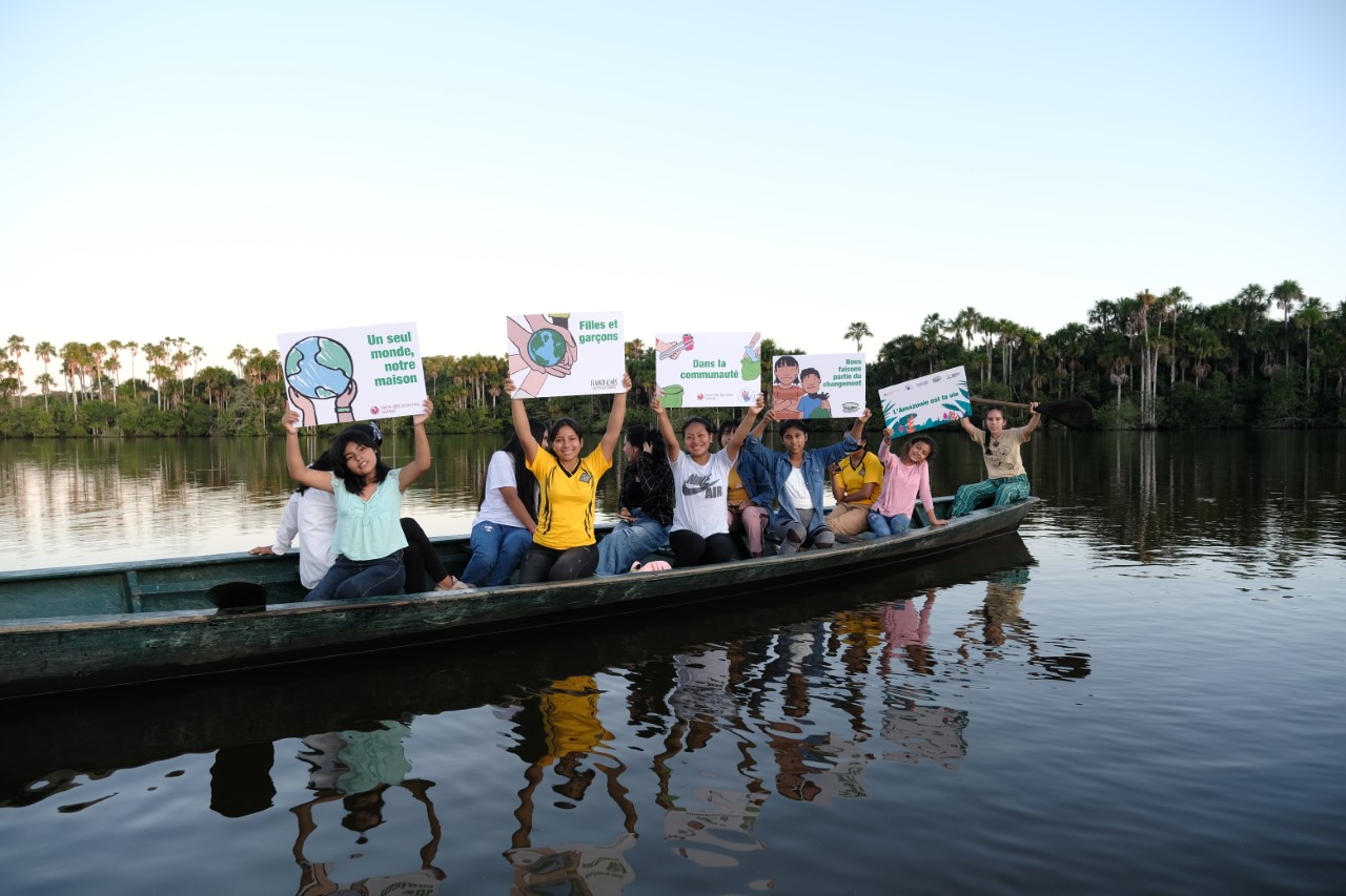 A group of people in a boat holding signs supporting the mission of terre des hommes suisse.