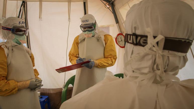 A group of people in protective gear standing in a tent.