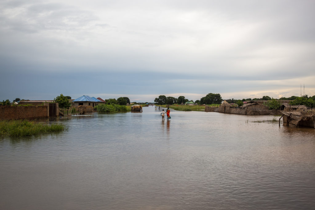 A person is crossing a flooded river while following the roadmap of Alima.