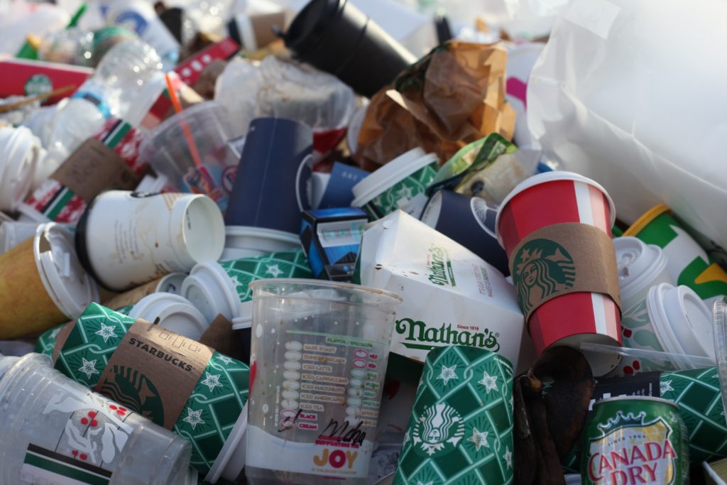 A pile of Starbucks coffee cups on the ground, highlighting efforts to eliminate unnecessary plastic packaging.