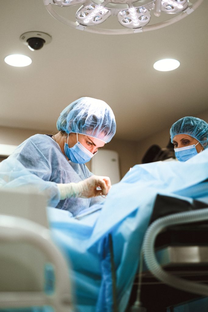 Two surgeons performing surgery in an operating room while the British NHS brings suppliers on its net-zero journey.