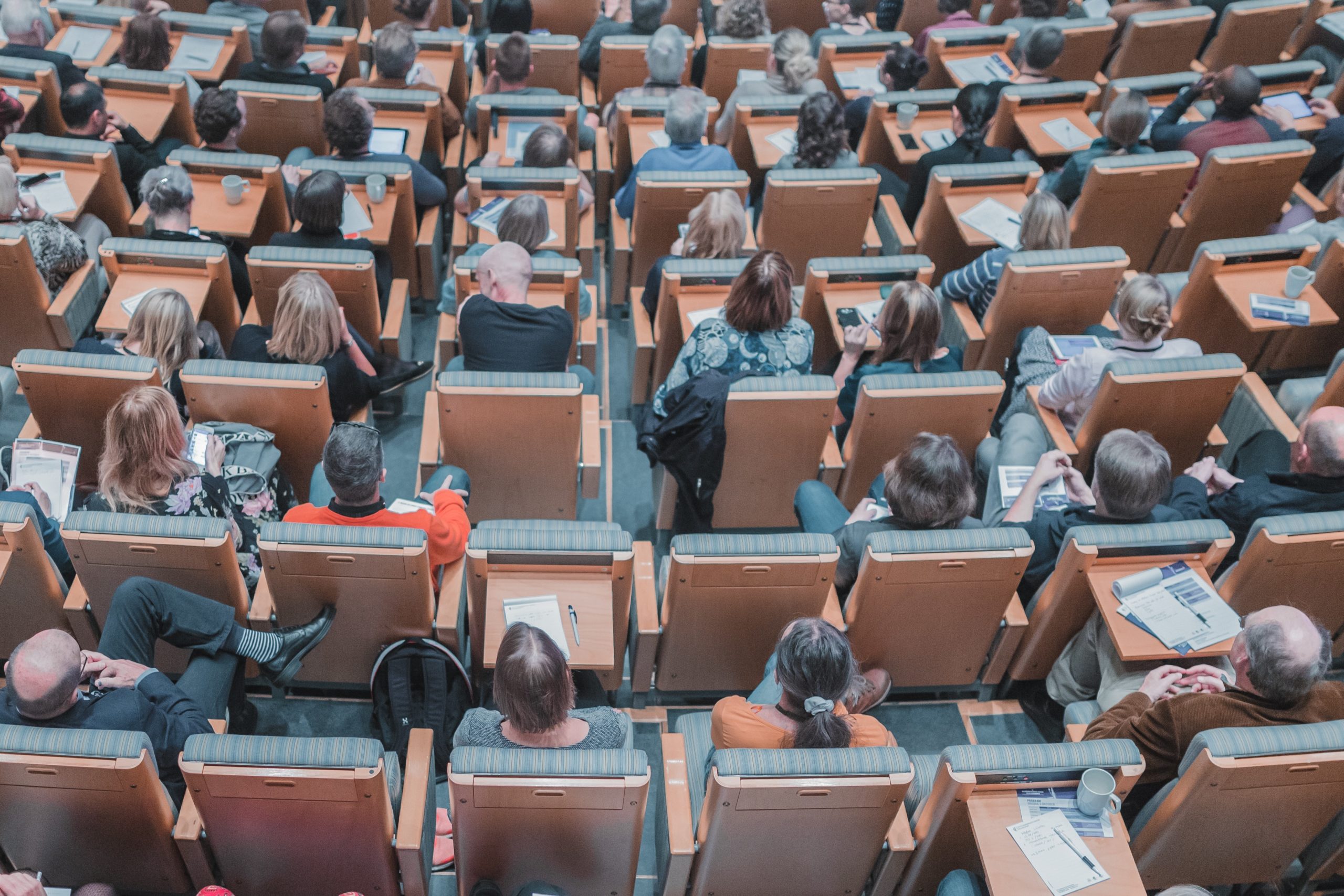 A large group of people sitting in a lecture hall, eagerly awaiting upcoming events.