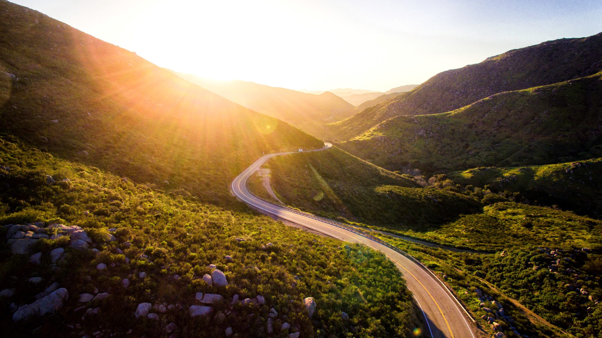 An aerial view of a winding road in the mountains showcasing stunning landscapes and minimal carbon footprints.
