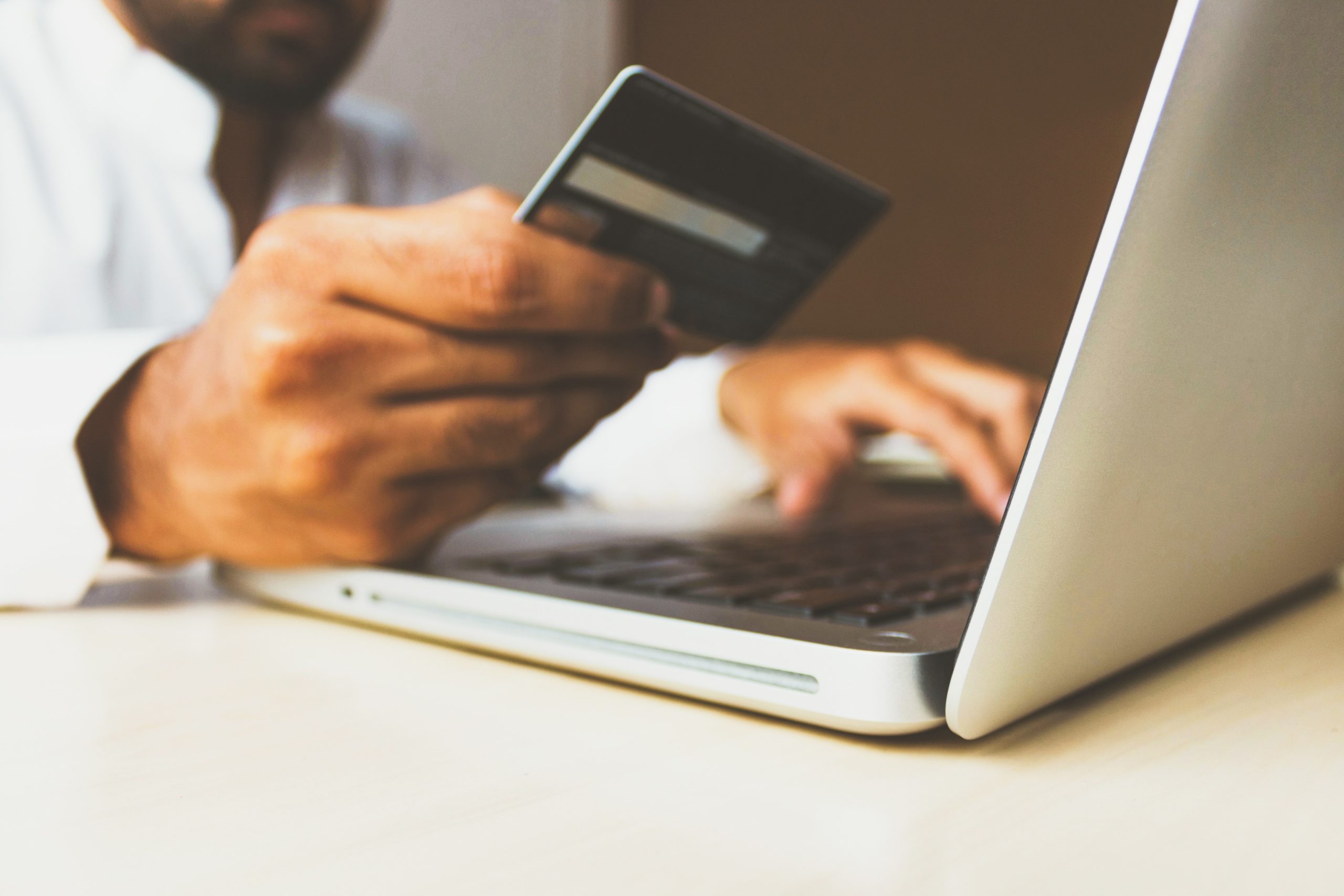 A man holding a credit card while using a laptop for online banking.