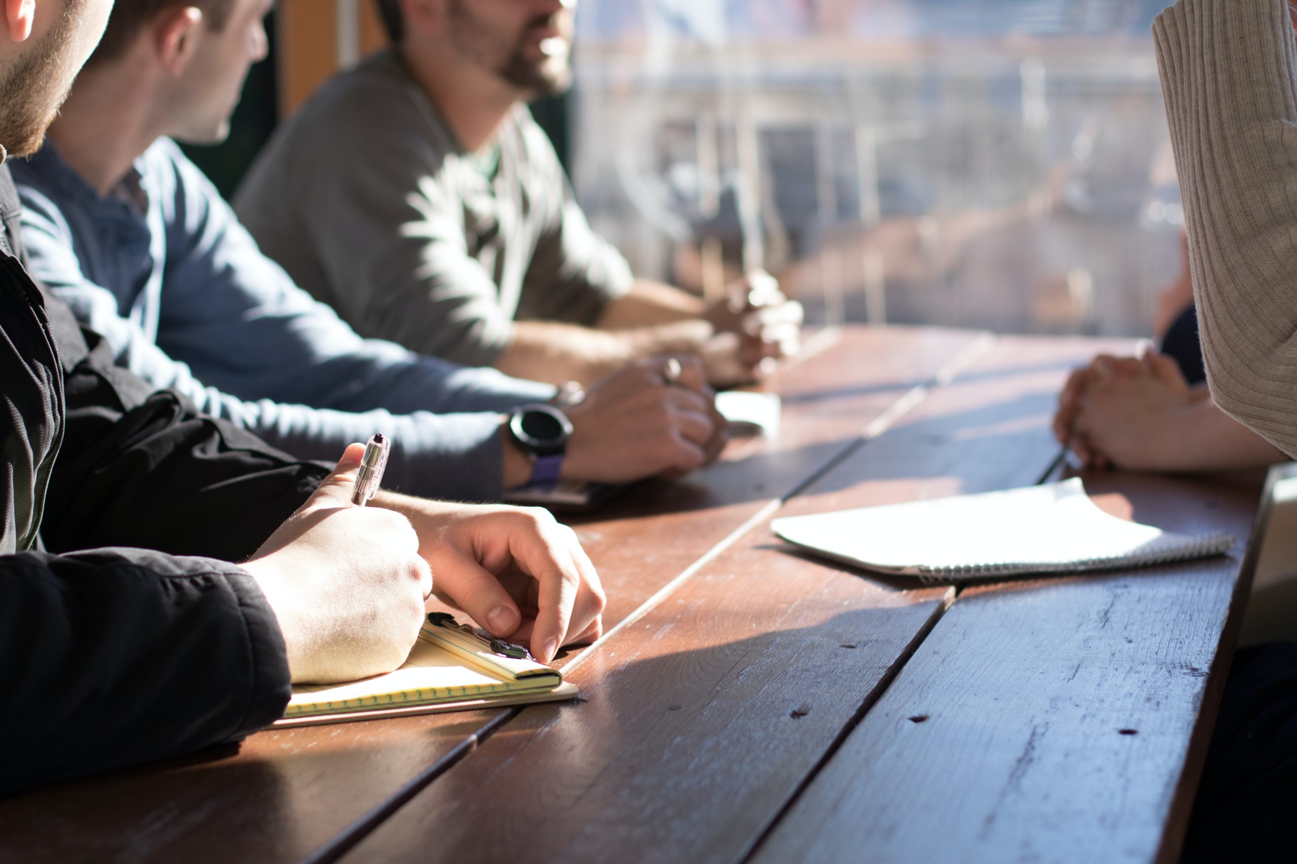 Un groupe de personnes assises autour d'une table en bois, engagées dans la communication et la sensibilisation.